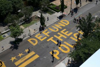 Photo of a street with 'defund the police' painted on it.