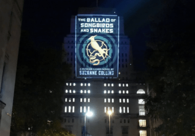 The cover of the Suzanne Collins book The Ballad of Songbirds and Snakes, projected onto a building. Intended to serve as a cover photo for the December 2023 Reading List.