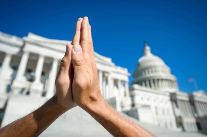 A set of hands in a prayer position in front of the Supreme Court.